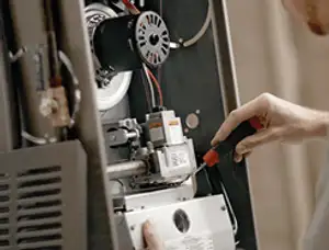 Furnace repair technician inspecting internal components and wiring in Worcester, MA