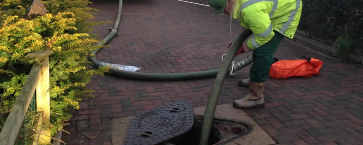 Septic tank cleaning technician servicing a septic tank with a vacuum hose in Worcester, MA