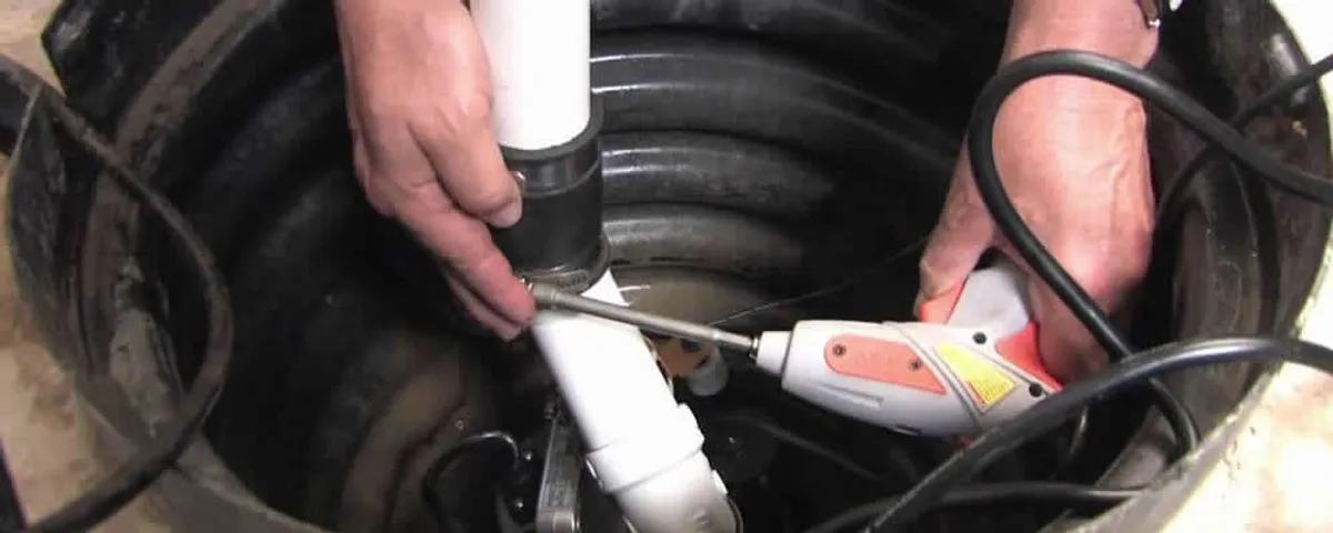 Sump pump installation technician connecting PVC discharge piping in Worcester, MA