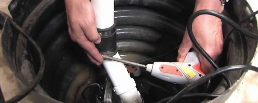 Sump pump installation technician connecting PVC discharge piping in Worcester, MA